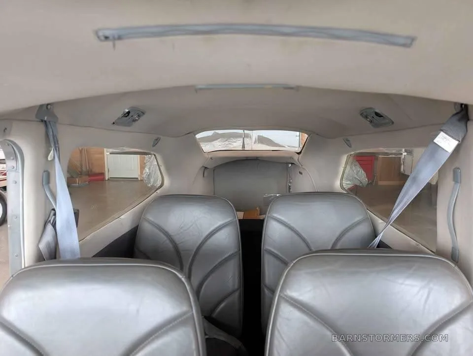 The gray leather interior cabin seats of a small aircraft, viewed from the rear.