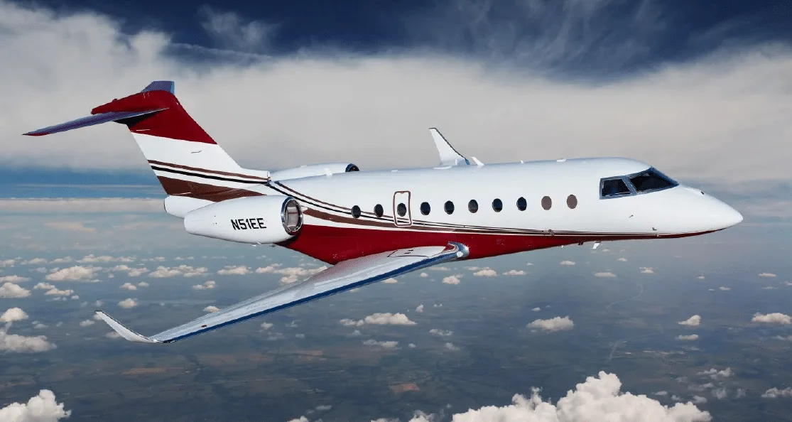 A white business jet with a red belly and brown stripe, tail number N51EE, flying above clouds.