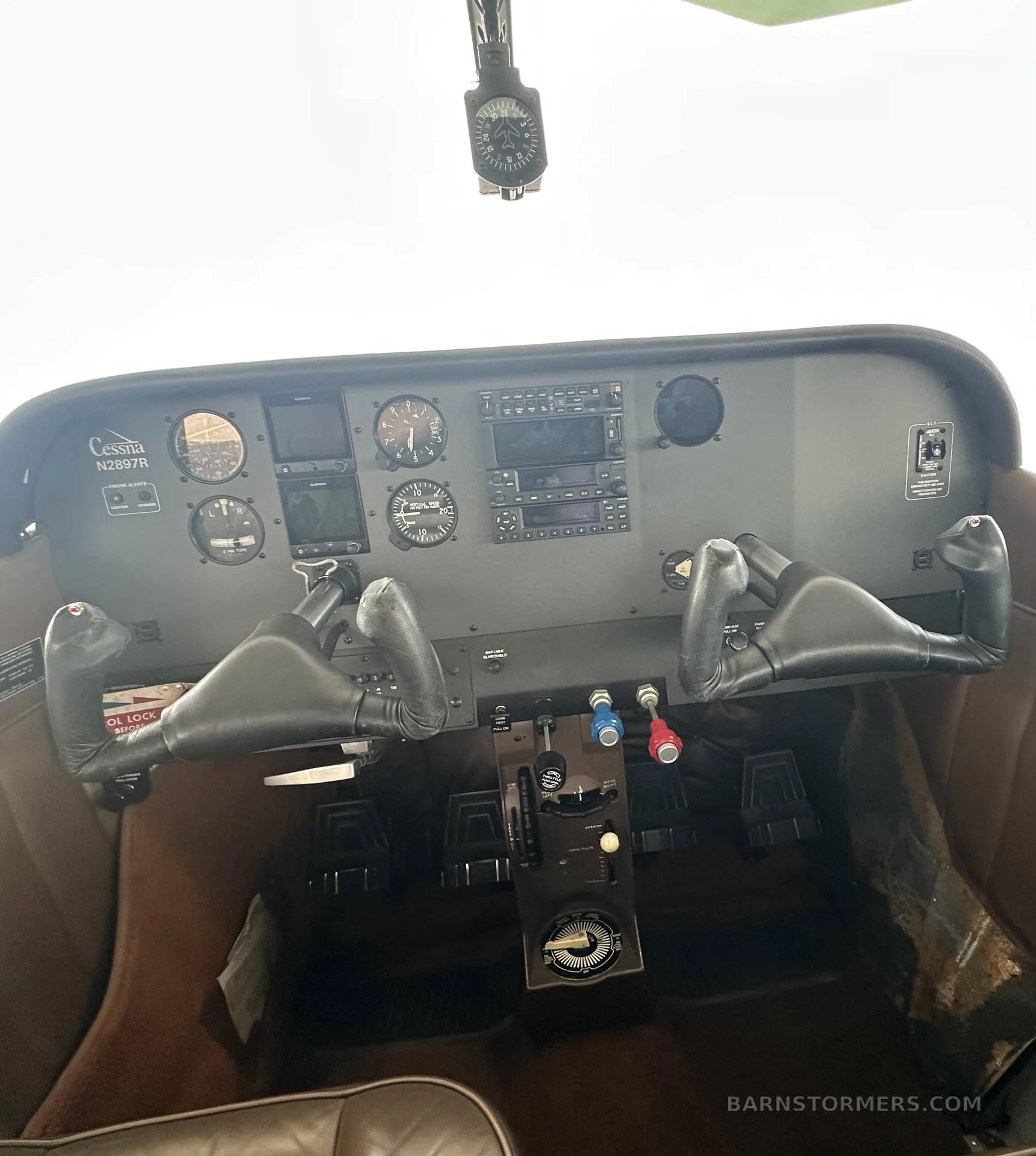 The cockpit of a Cessna N2897R, showing the instrument panel with analog gauges, avionics, and two control yokes.
