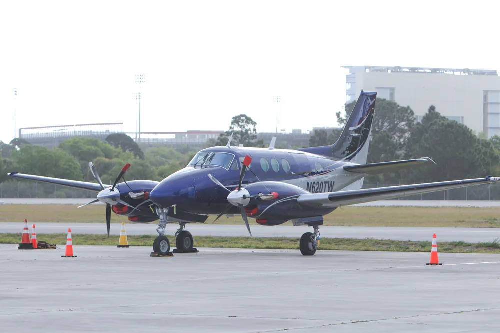 A blue and white twin-engine turboprop aircraft, N620TW, parked on a tarmac with buildings in the background.