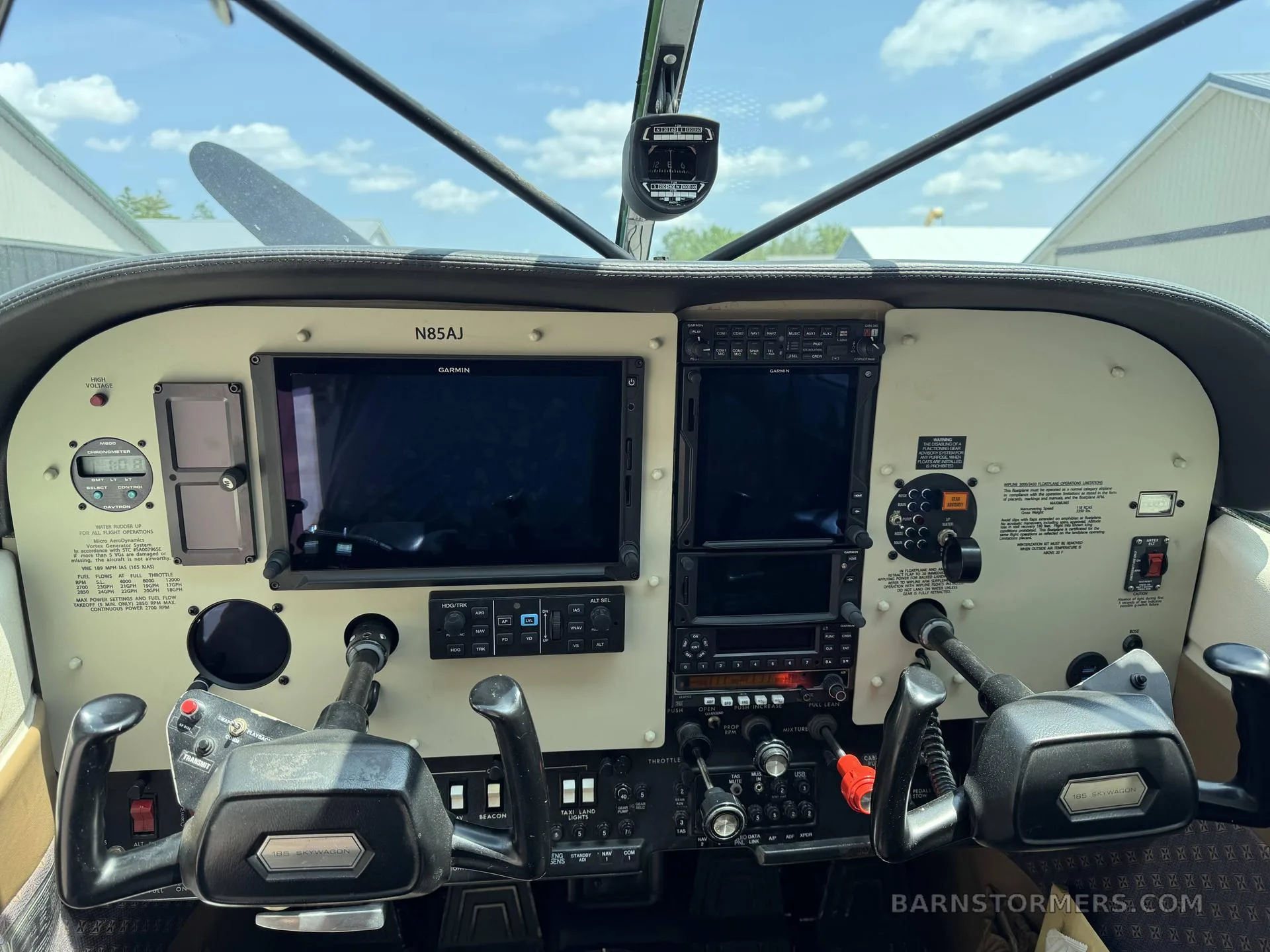 The cockpit of a floatplane features a modern avionics panel with two large Garmin displays and dual yokes.