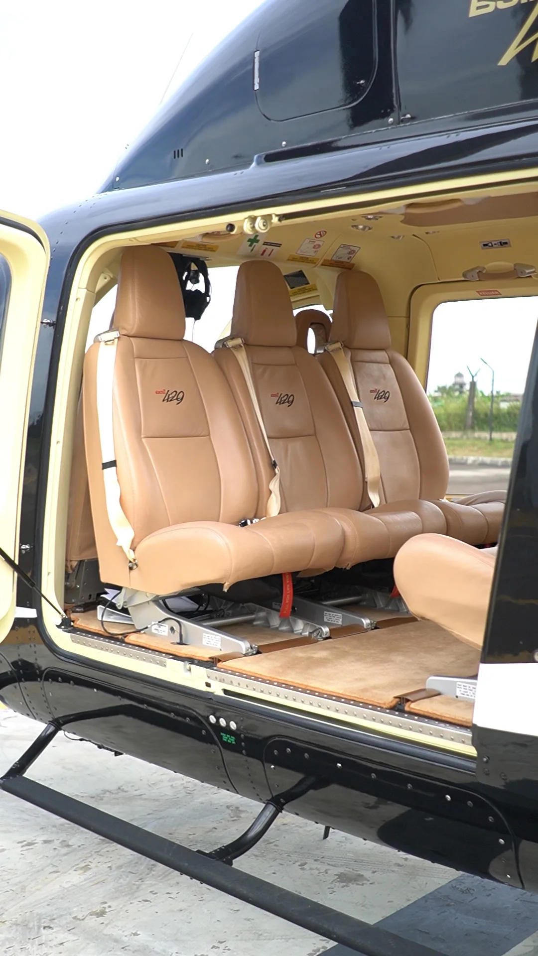View of the helicopter cabin with tan leather seats and open door.