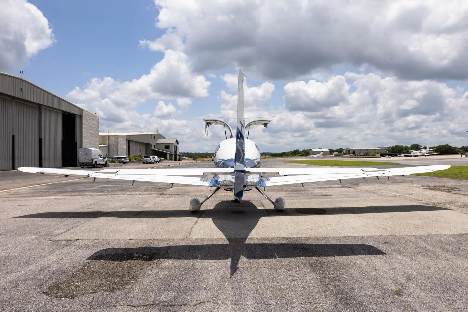 A rear view of the Cessna TTX N530JM with its gull-wing doors open, parked on a tarmac.