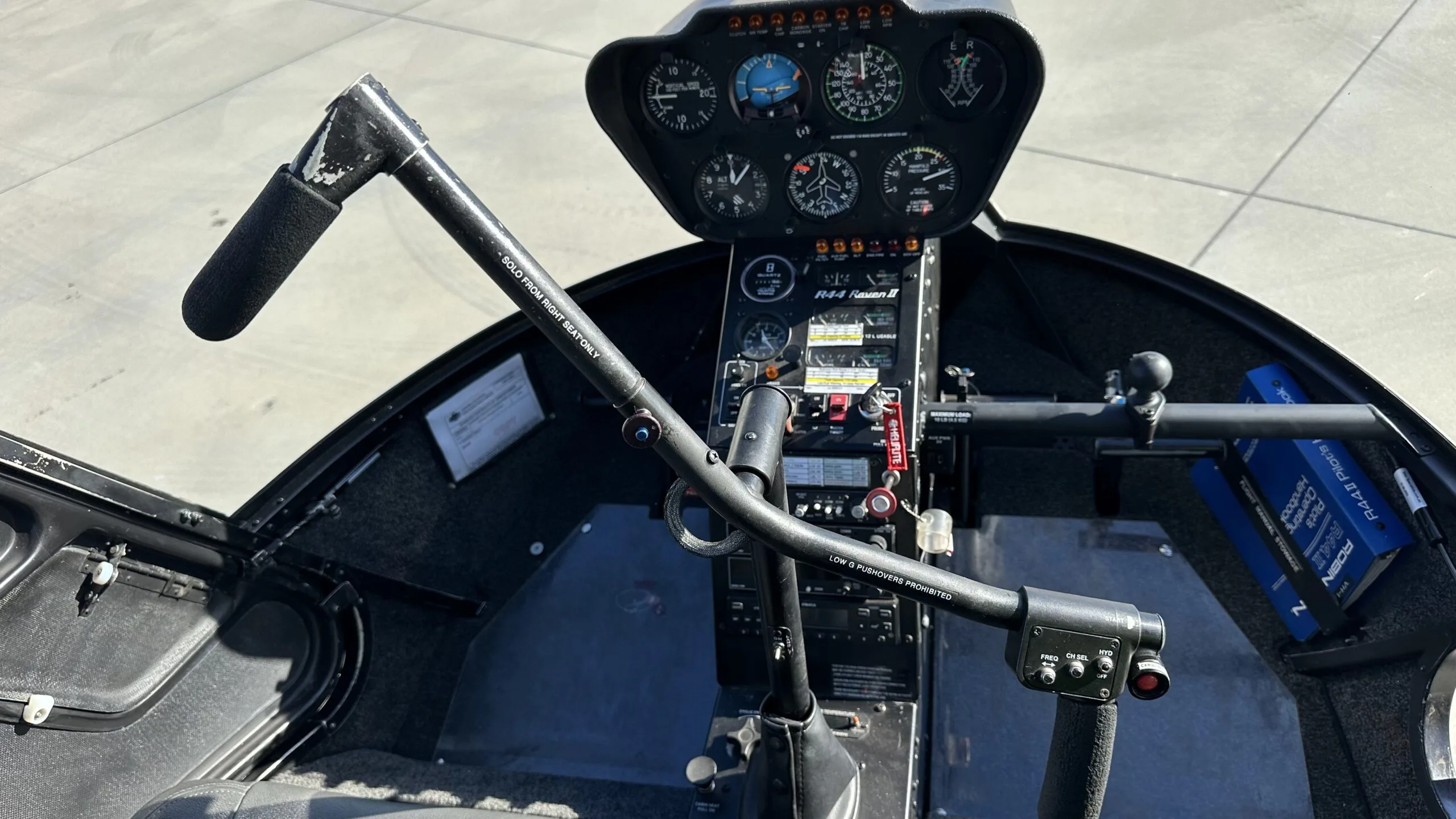 The cockpit of a Robinson R44 helicopter showing the instrument panel and cyclic control stick.