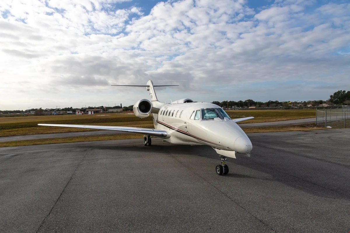 A Citation X aircraft parked on the tarmac under a cloudy sky.