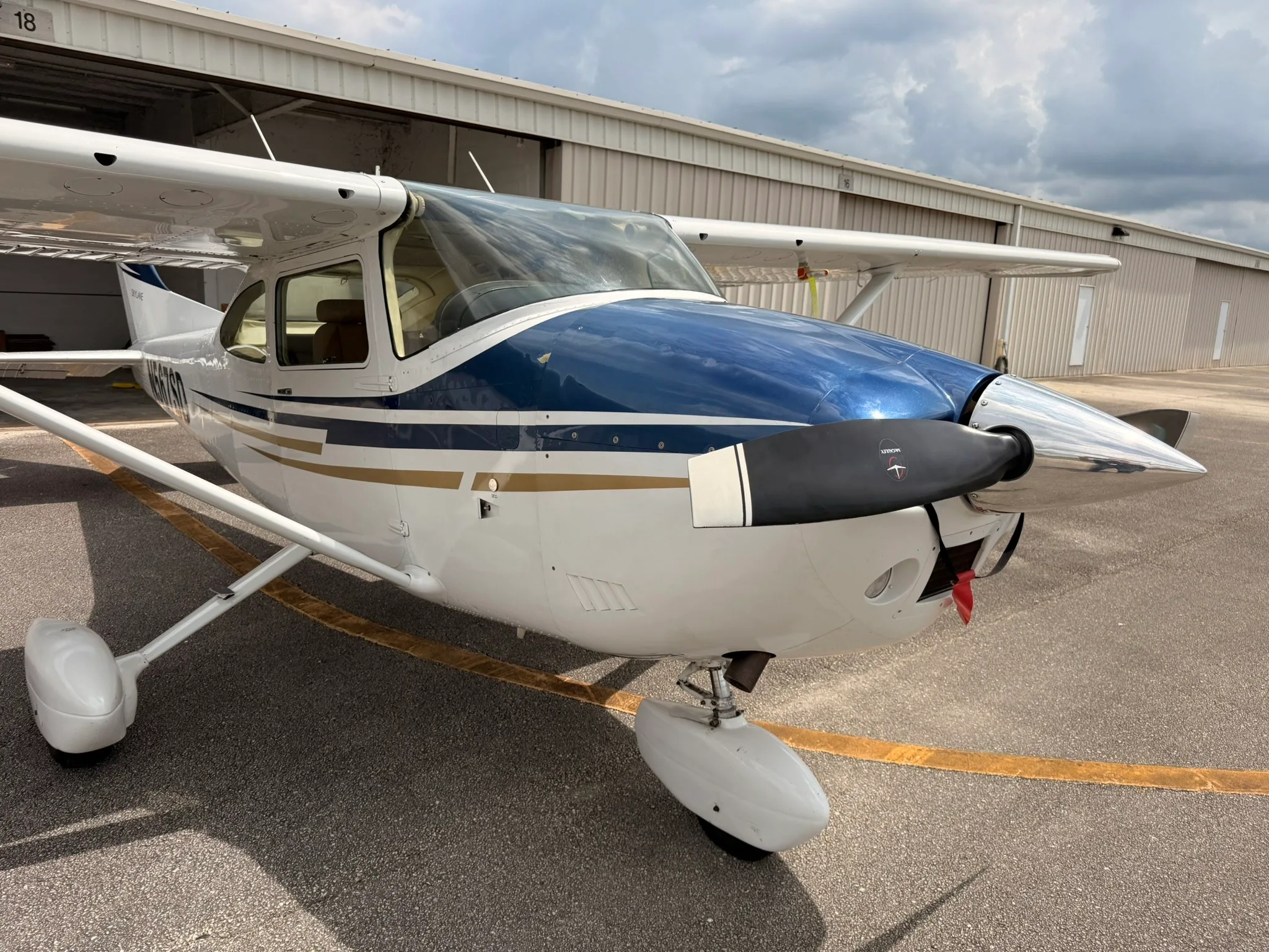 A front-right view of the Cessna Skylane N567SD, highlighting the blue and gold paint scheme on the nose.