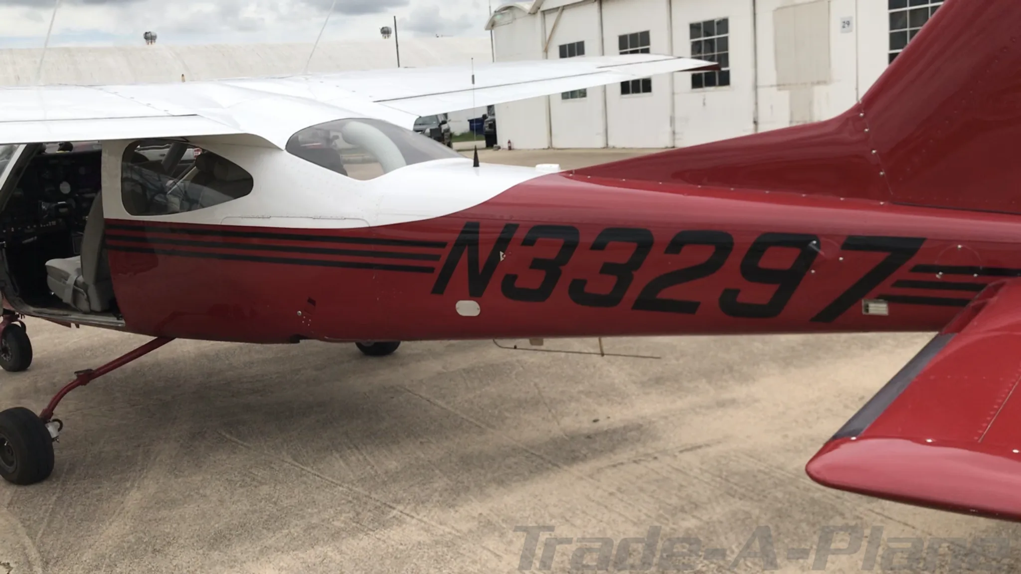 A close-up side view of the red and white N33297 aircraft fuselage, clearly showing the registration number and black stripe details.