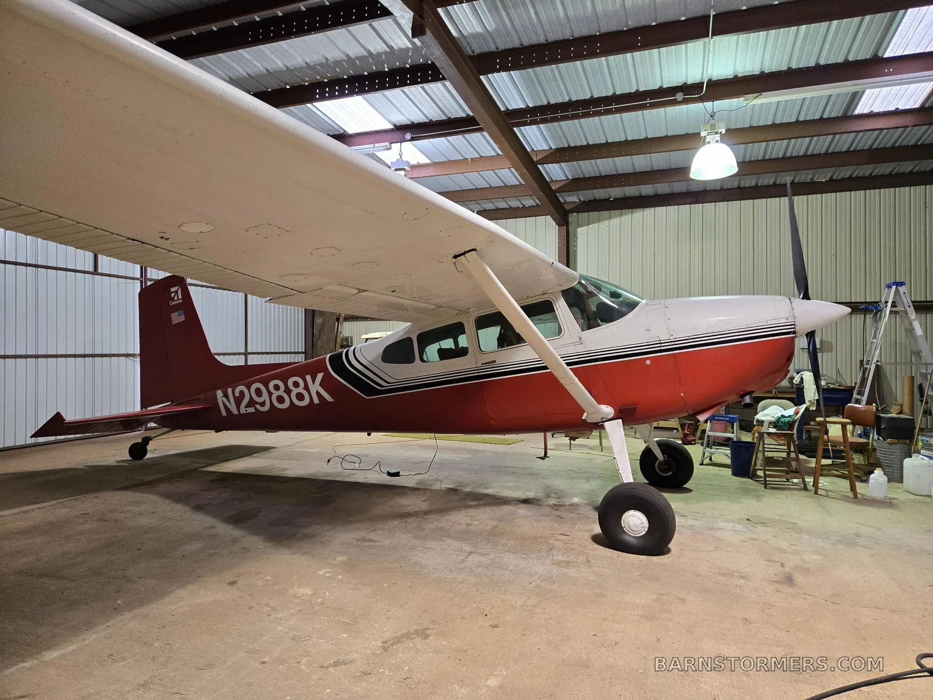 A red and white single-engine propeller aircraft with registration N2988K parked inside a hangar.