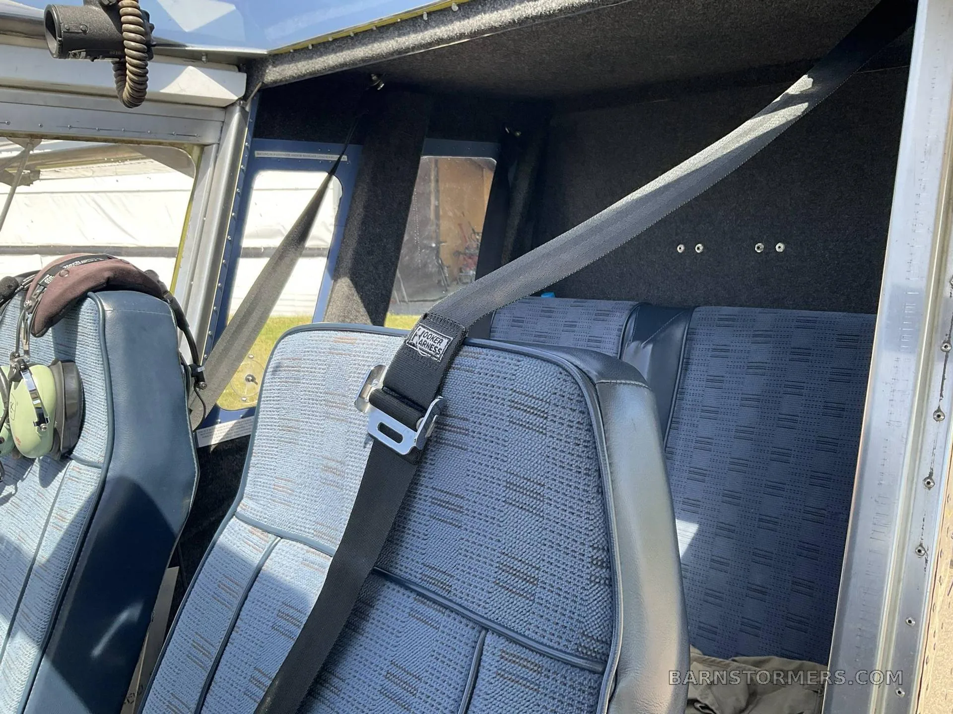 The blue patterned fabric seats and seatbelts in the interior cabin of an aircraft.