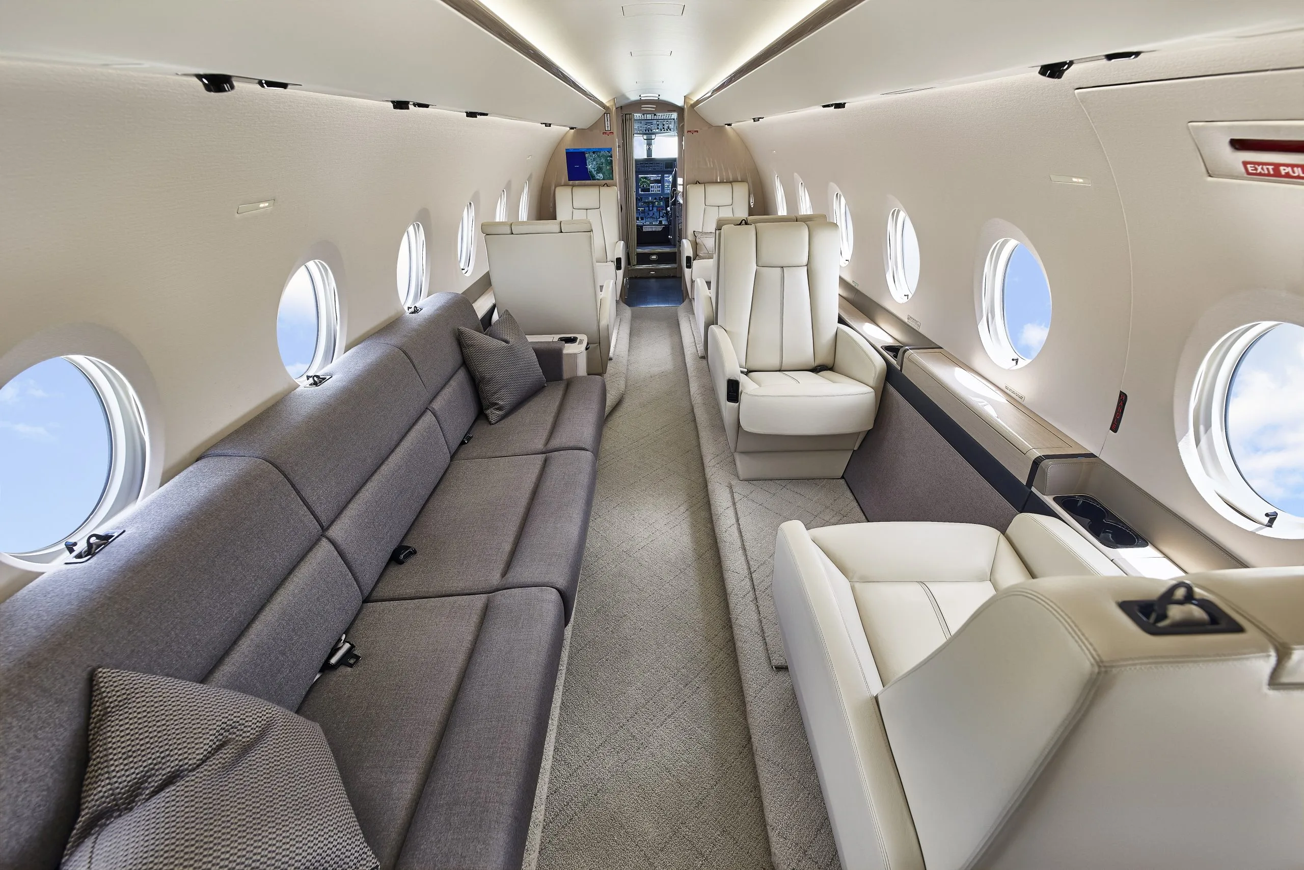 Forward view of the aircraft interior with gray sofa and white leather seats.