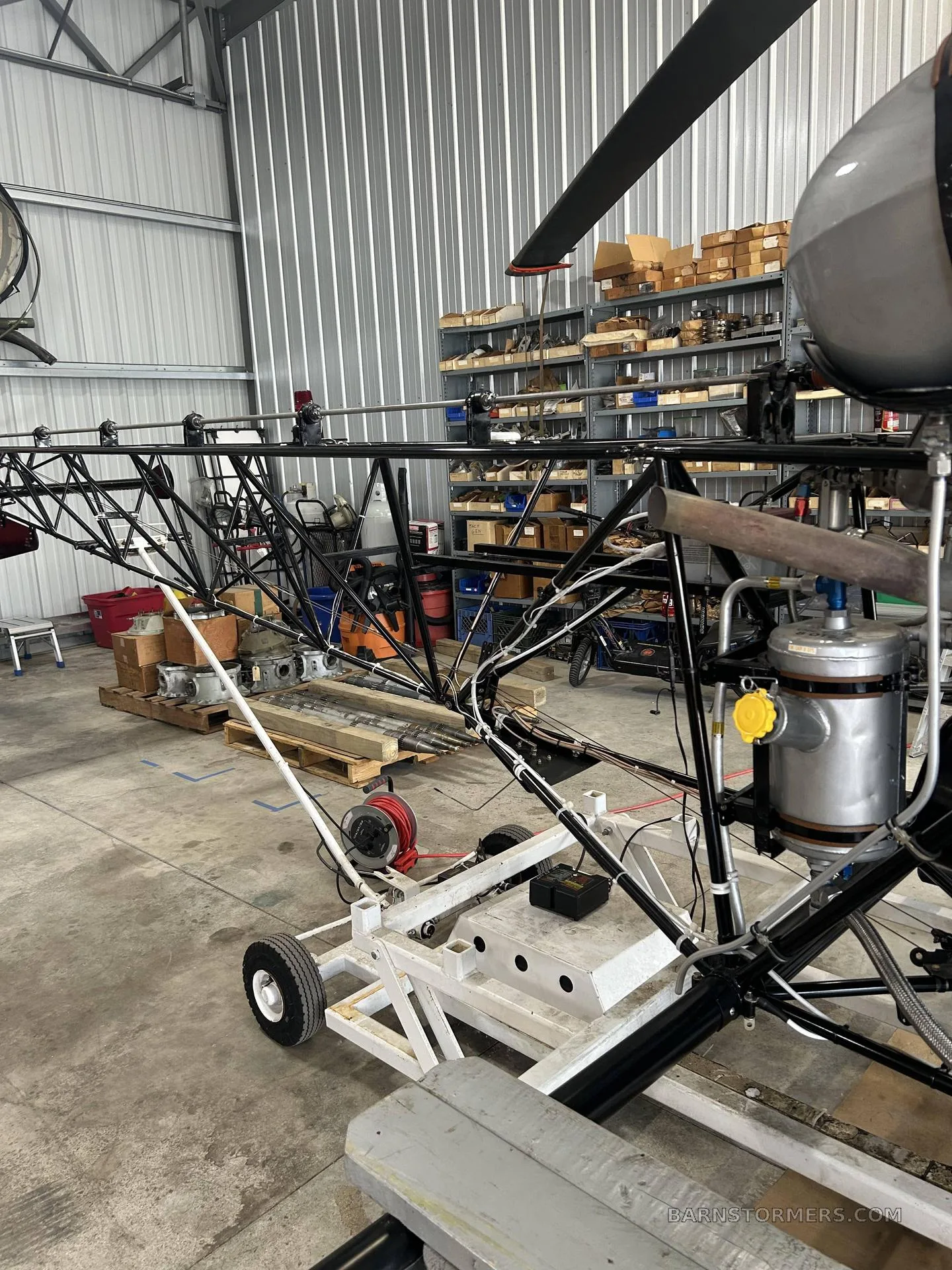 The exposed metal frame of a helicopter's tail boom and engine components in a hangar.