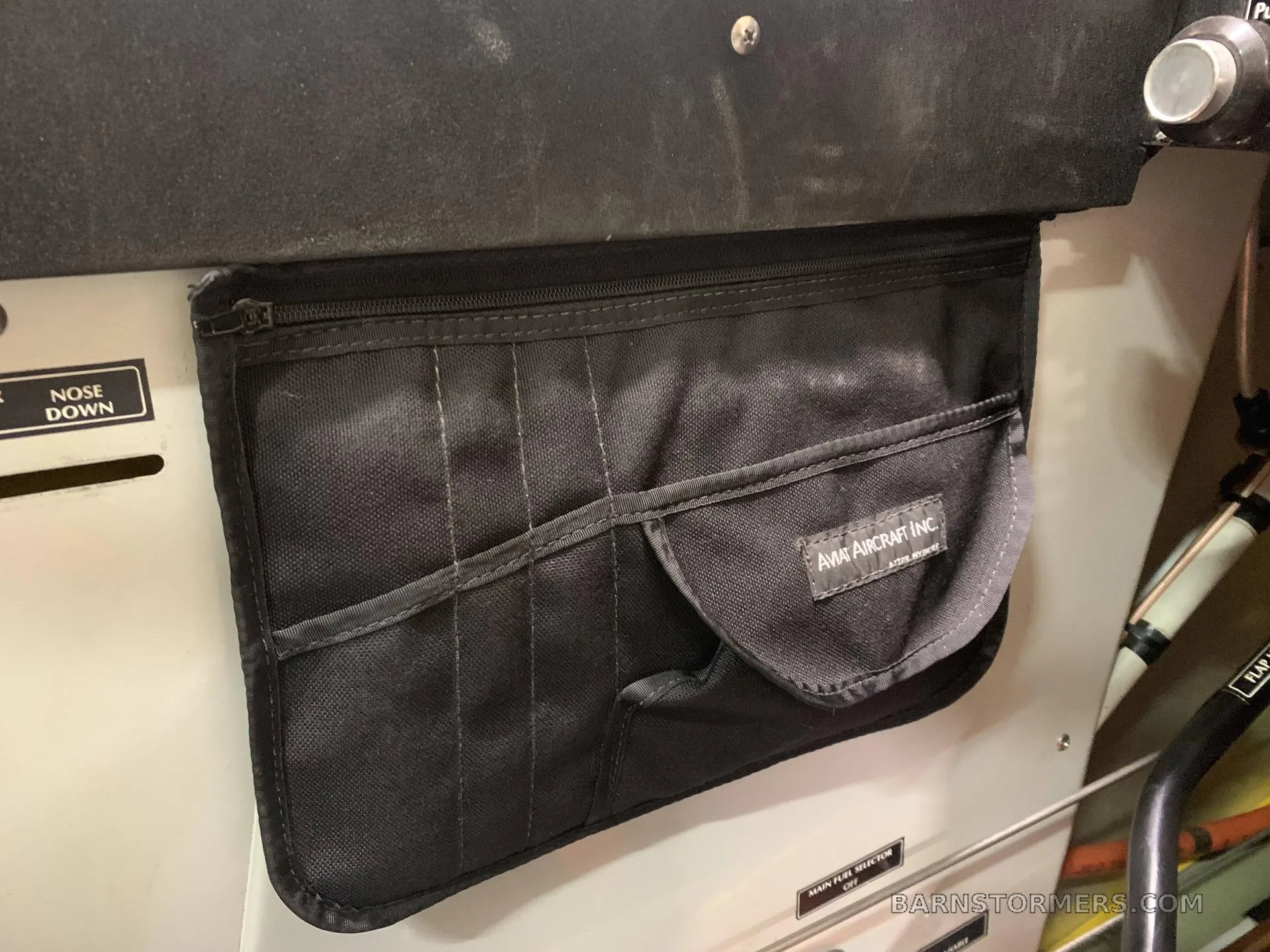 A black storage pouch with "AVIAT AIRCRAFT INC." logo attached to an interior panel of the aircraft.