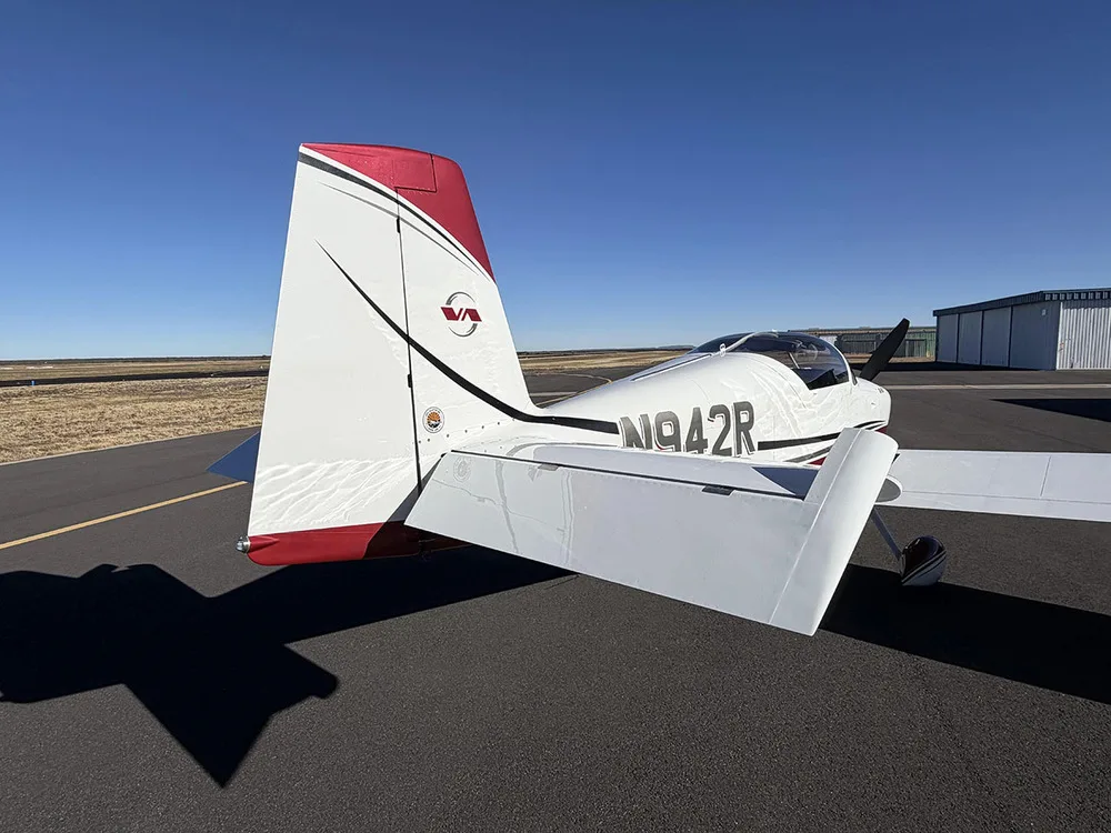 A rear-quarter view of the white and red Van's RV-9A aircraft N942R showing the tail and right wing.