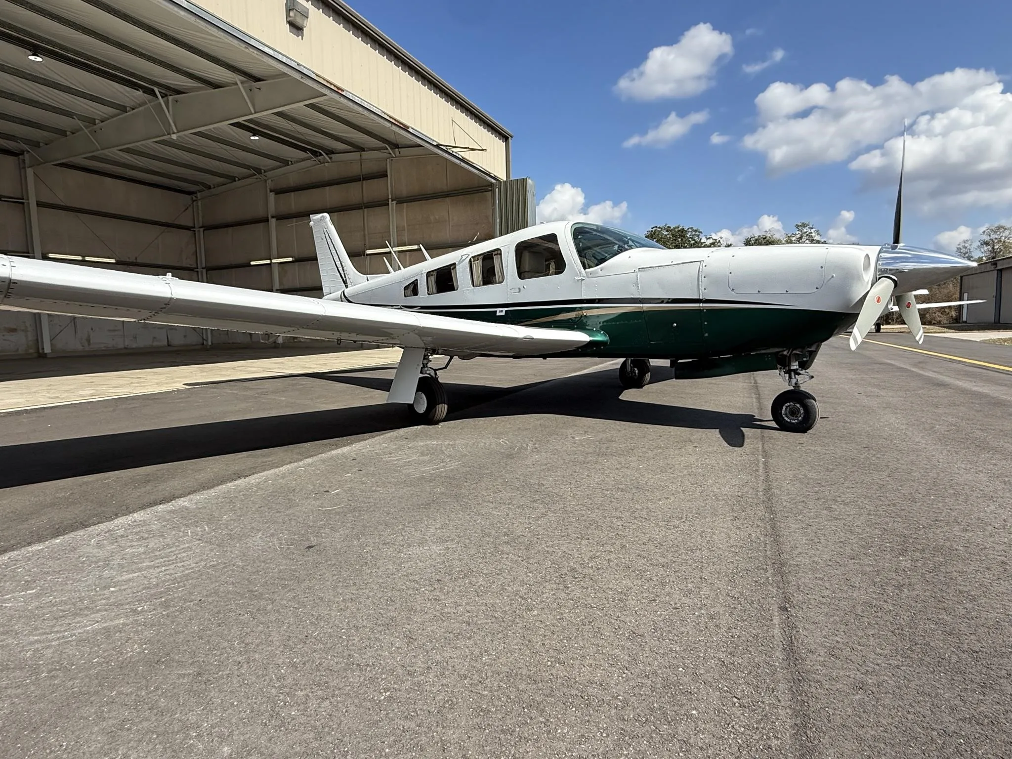 A low-angle view of the white and green Piper PA-32R-300 Cherokee Lance II (N4516Q) parked on an asphalt ramp.