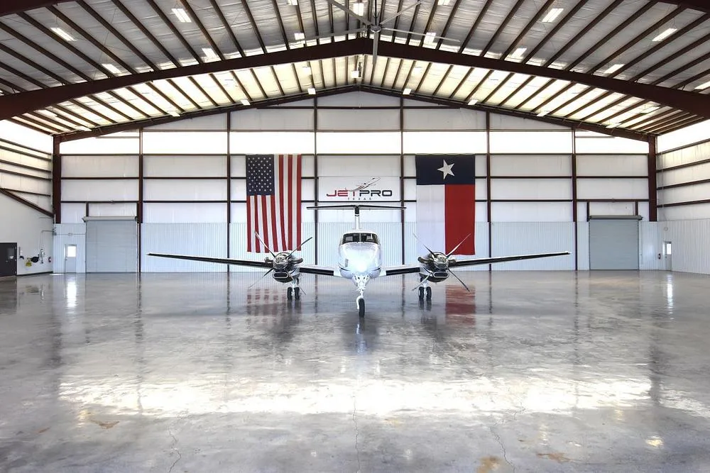 A head-on view of the white and blue Beechcraft King Air twin-engine turboprop aircraft, N627MG, in a hangar.