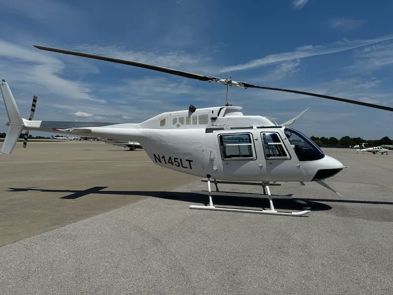 Side view of a white Bell 206L-4 helicopter with tail number N145LT on the tarmac.