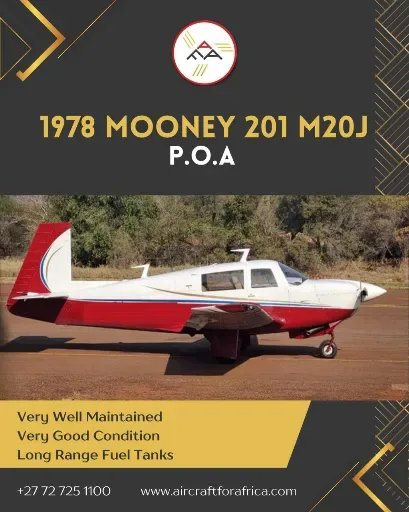 A white 1978 Mooney 201 M20J with red and blue stripes is parked on a tarmac with trees in the background.