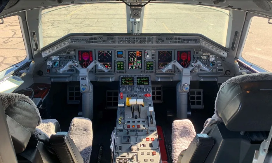The cockpit of an Embraer Legacy 650, showing the instrument panel with multiple displays, yokes, and pilot seats.