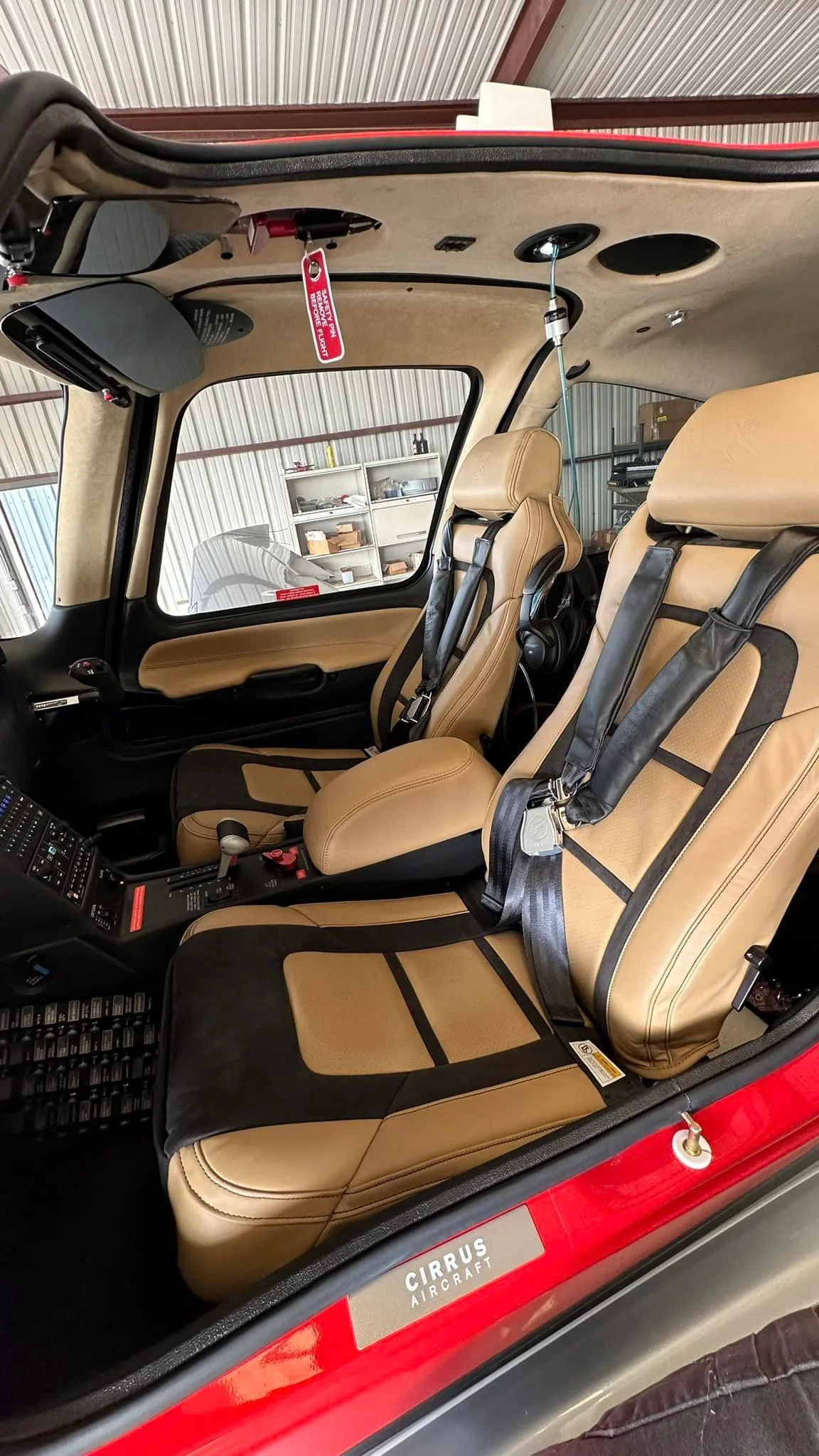 The tan and black leather seats of a Cirrus SR22 aircraft cabin, viewed from the front looking towards the rear.