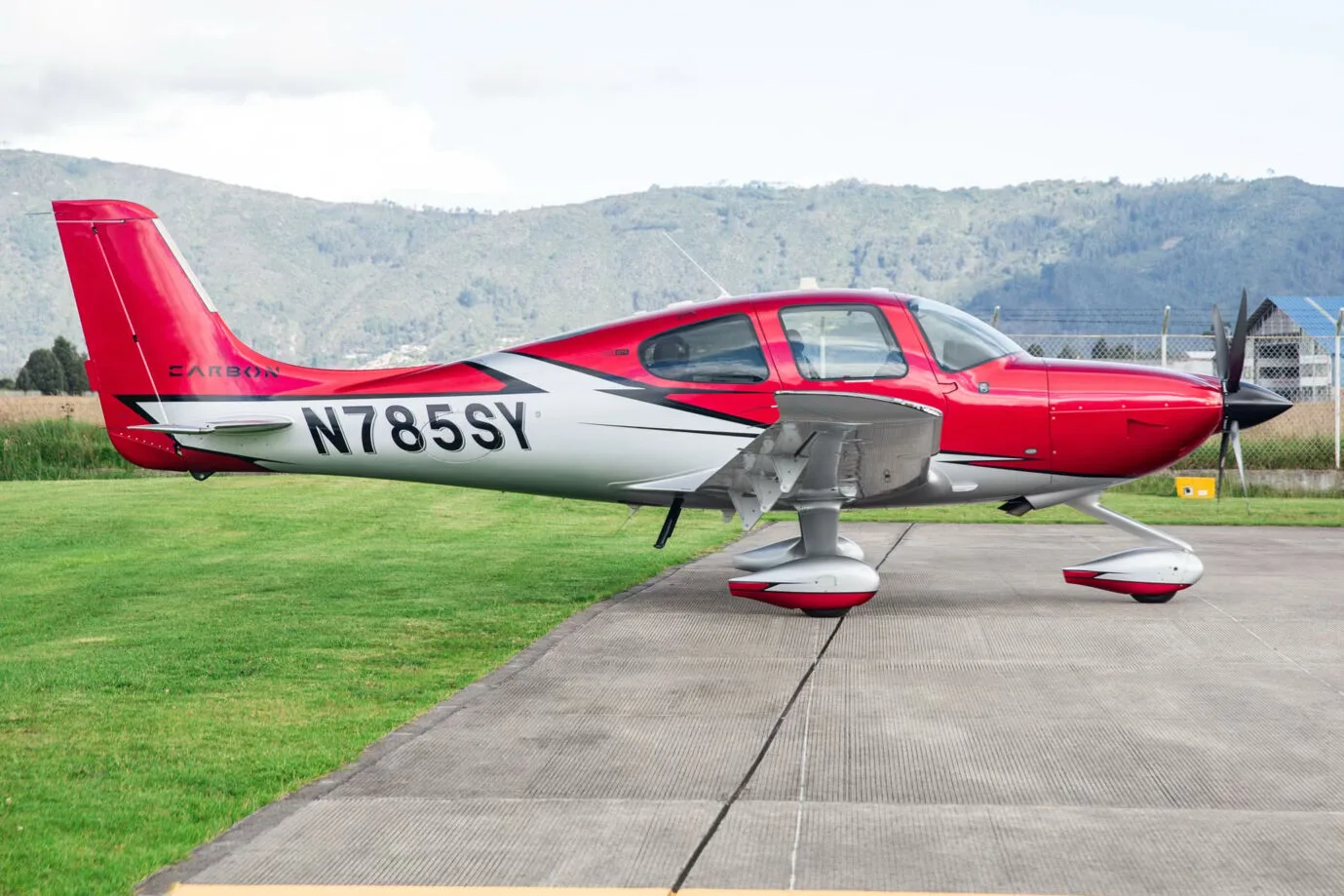 Side view of a red and silver Cirrus SR22T aircraft, registration N785SY, parked on an airfield.