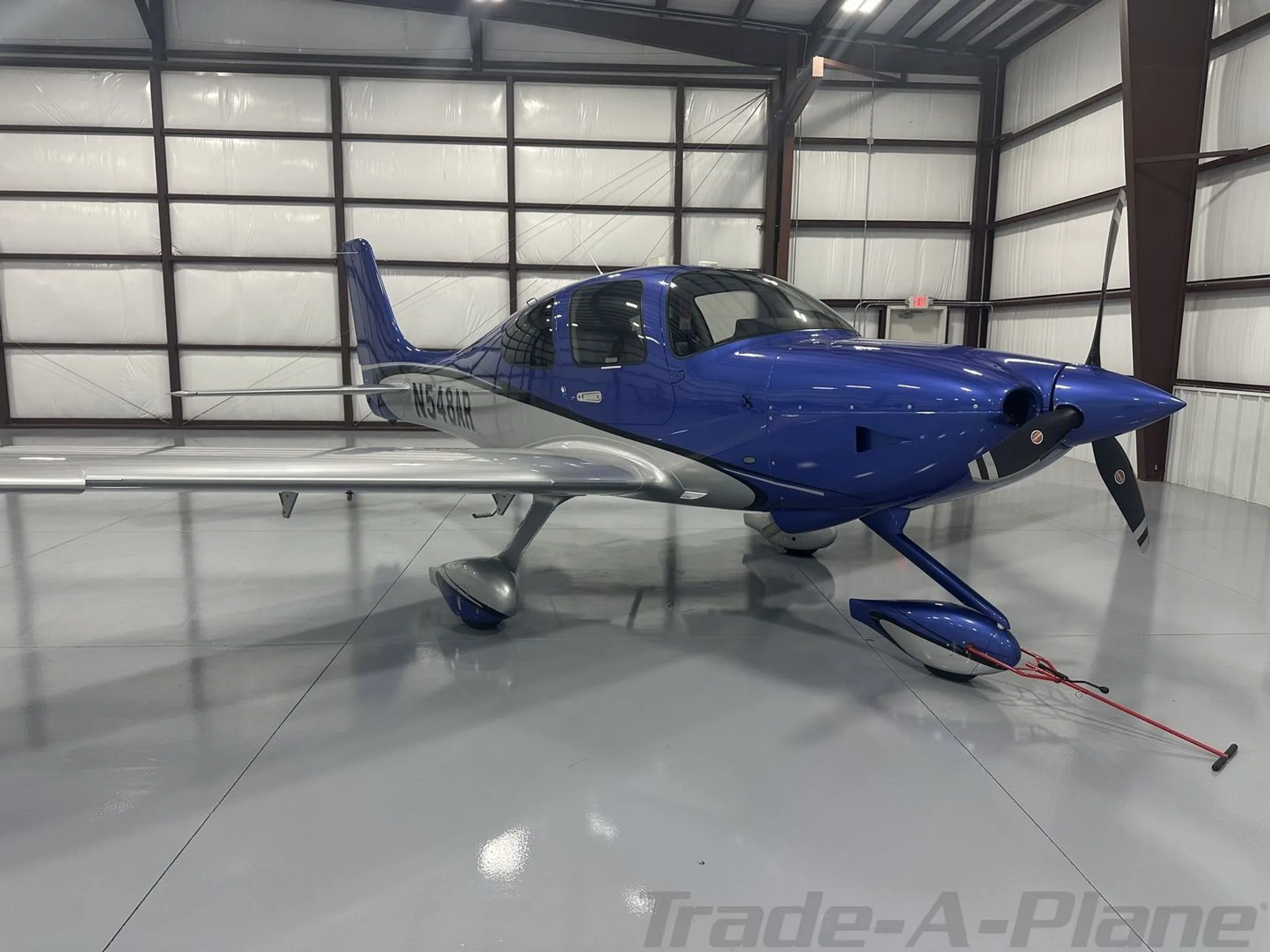 A front-side view of the blue and silver Cirrus SR22 aircraft N548AR in a hangar.