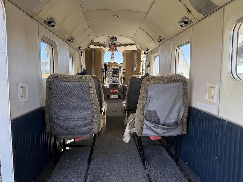 The interior cabin of an aircraft with sheepskin-covered seats, looking towards the cockpit.