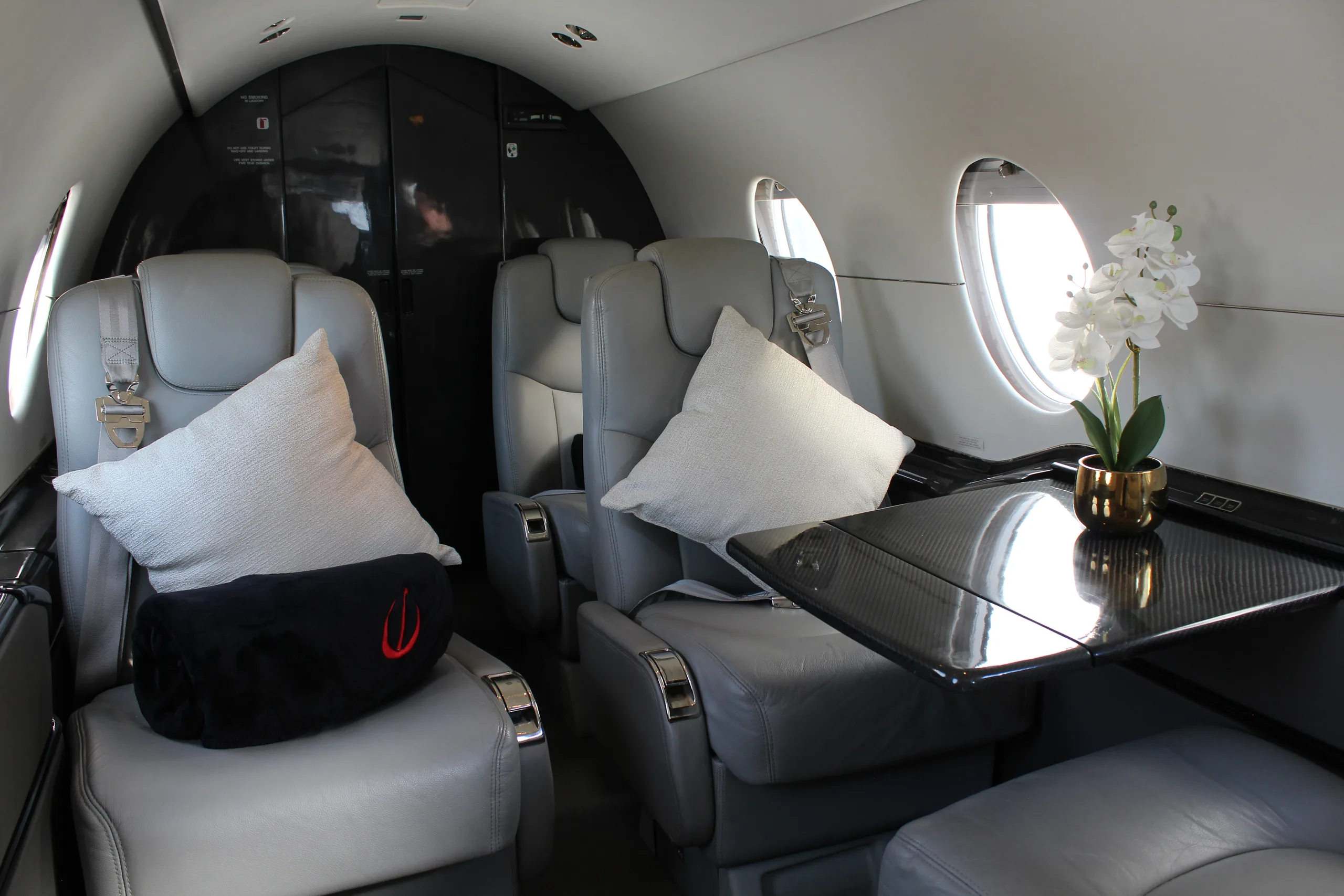 Interior view of the aircraft cabin with gray leather seats and a small table.