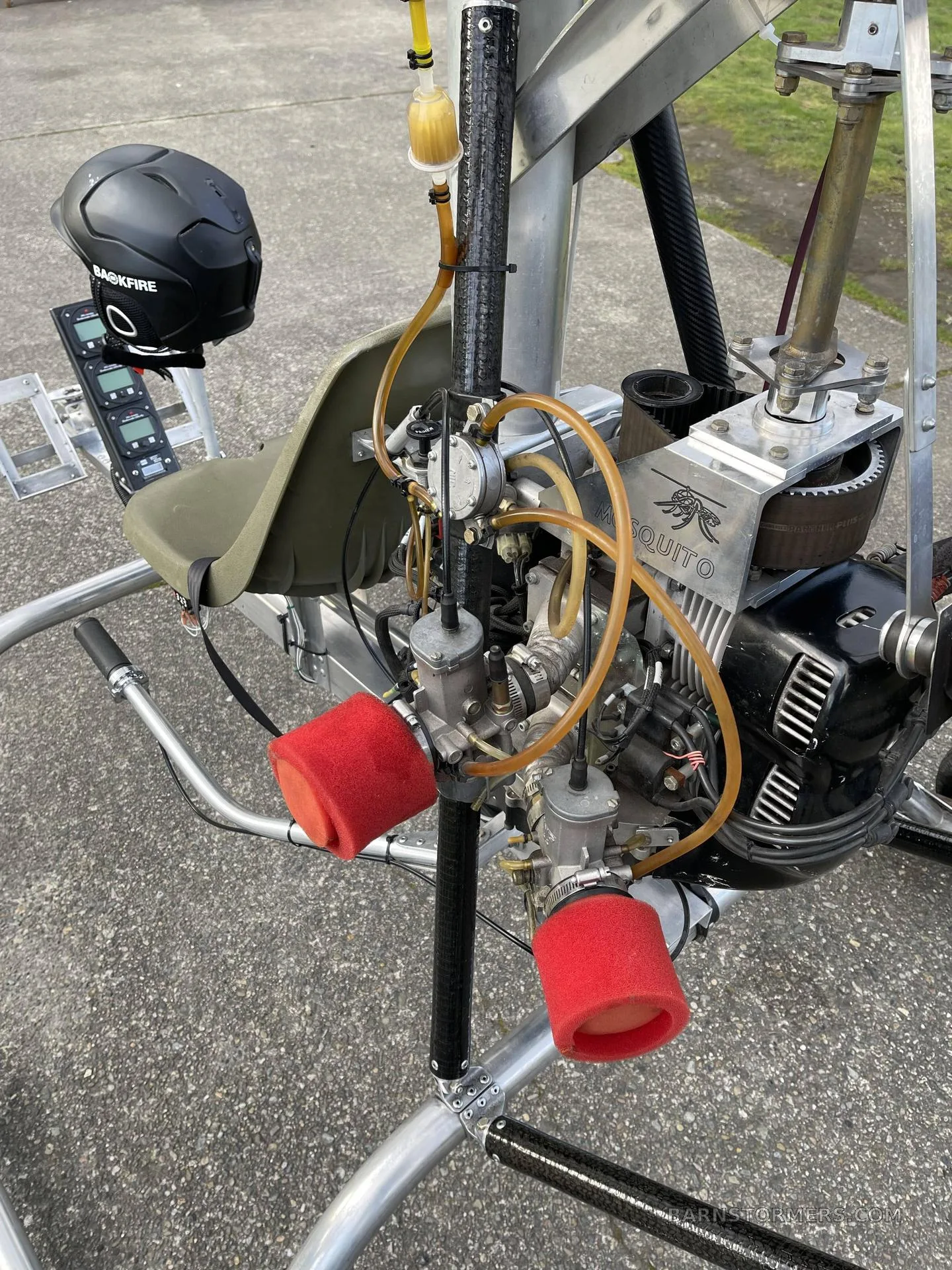 A close-up view of the "MOSQUITO" engine with red air filters and fuel lines on an ultralight helicopter.