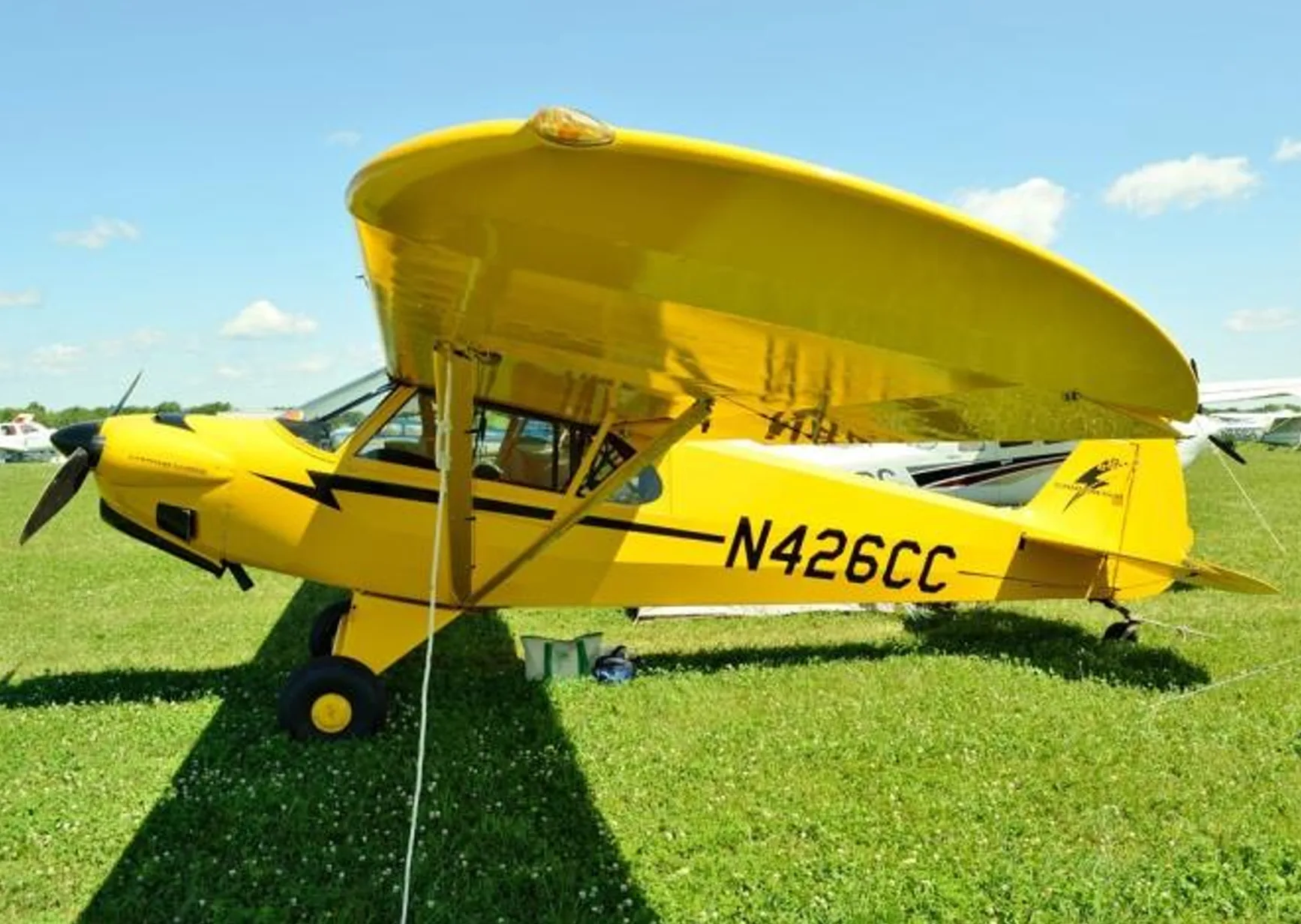 A yellow Carbon Cub aircraft, registration N426CC, parked on a grassy field.
