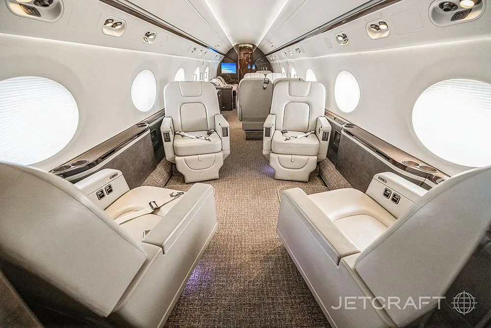 The luxurious cabin interior of a Gulfstream G650 features light cream leather seats and a spacious aisle.