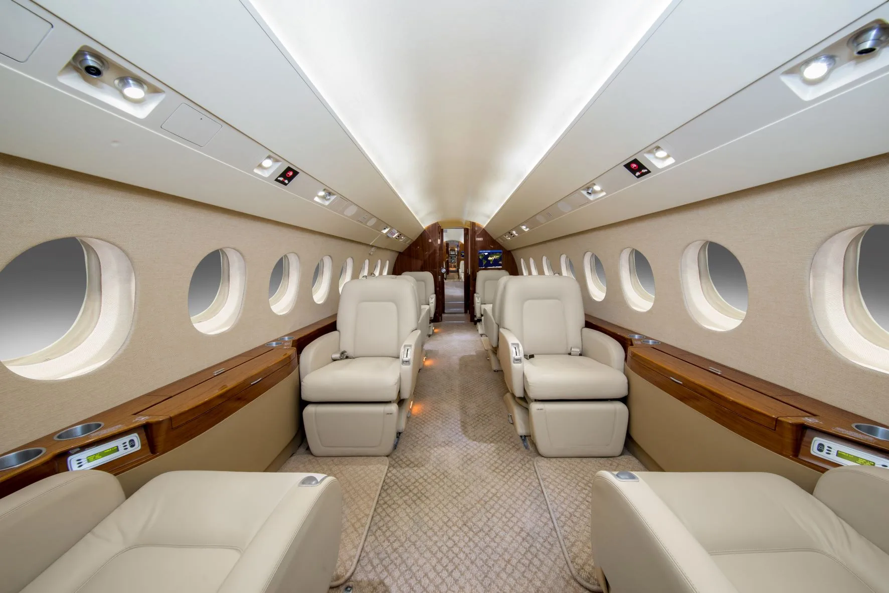 A luxurious aircraft cabin with light-colored leather seats and wood accents, looking towards the rear.