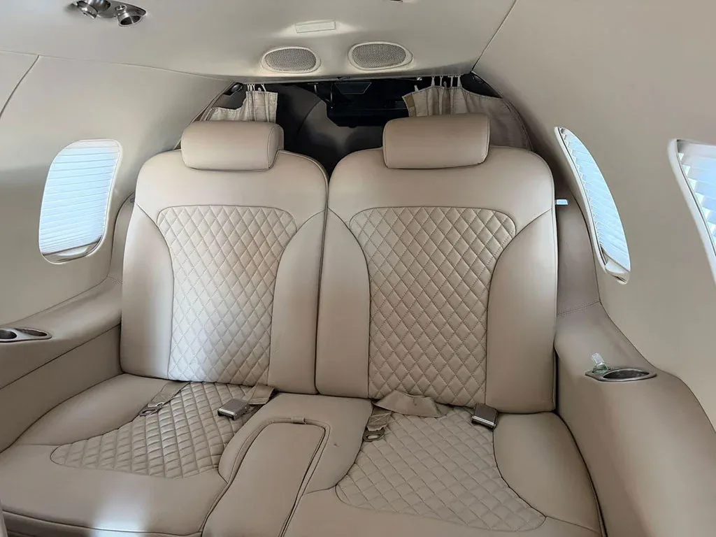 A view of two light beige quilted leather seats in the aircraft cabin.