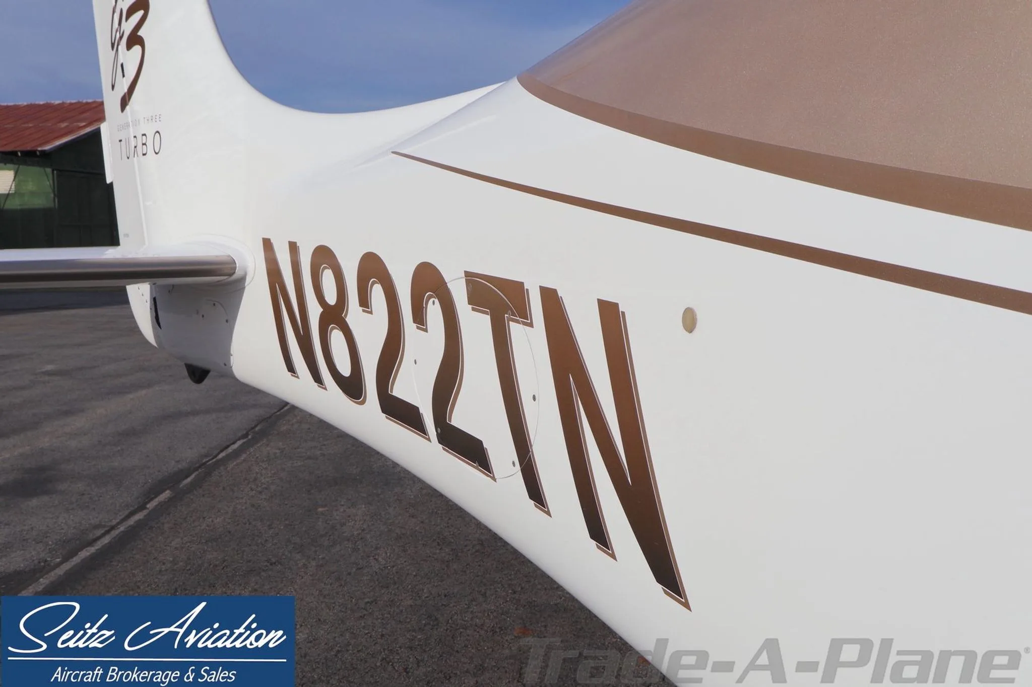 Close-up of the Cirrus SR22T aircraft's fuselage, showing the N822TN registration in gold lettering on a white background.