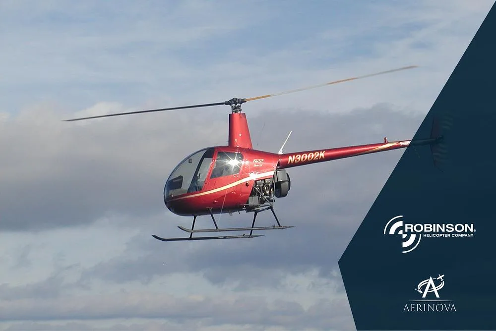 A red Robinson R22 helicopter with registration N3002K flies against a cloudy sky.