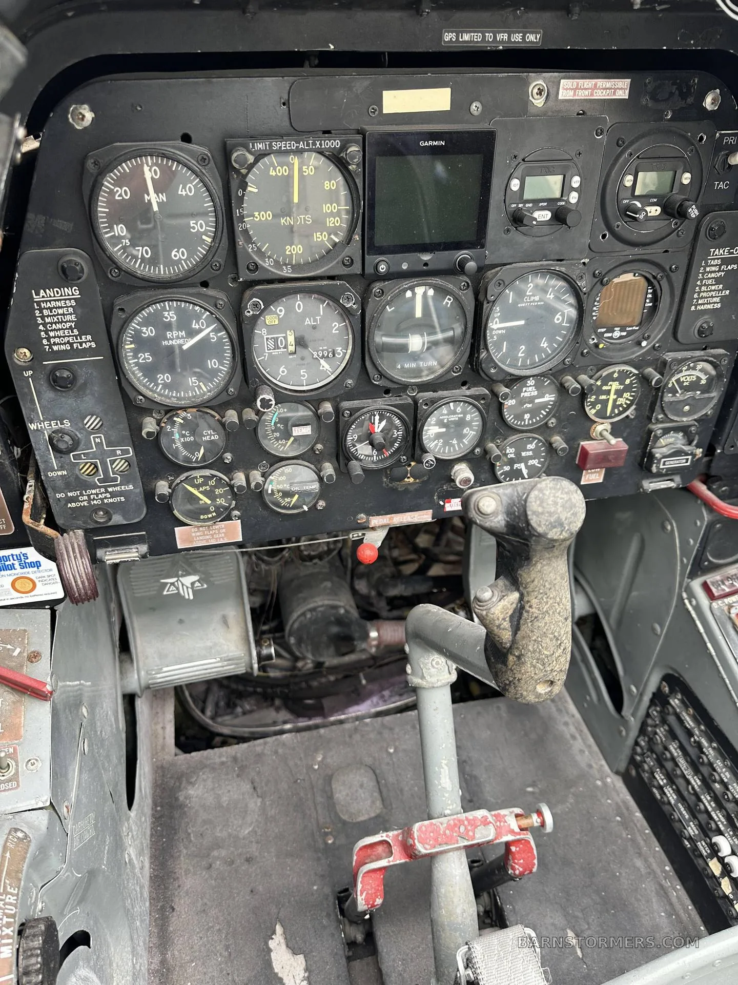 A close-up view of the instrument panel and control stick in a vintage aircraft cockpit, showing various gauges and switches.