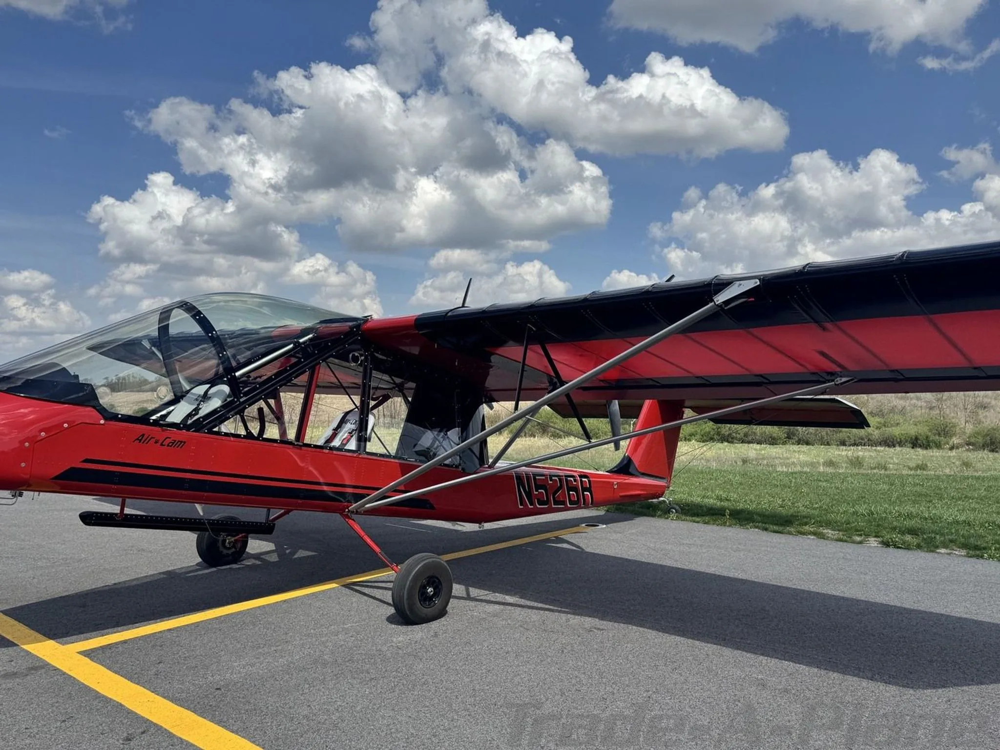 A red and black Air-Cam aircraft with registration N526R is parked on an airfield, viewed from the front-right side.