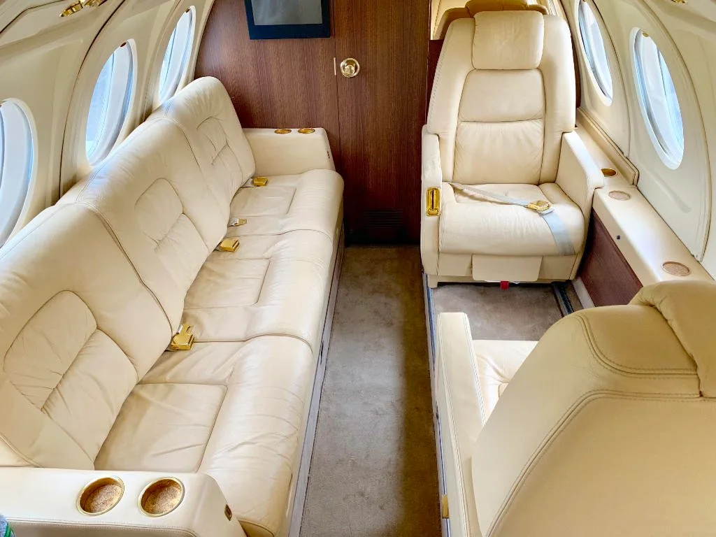 A view of the aircraft's interior with cream-colored leather seats and a couch.