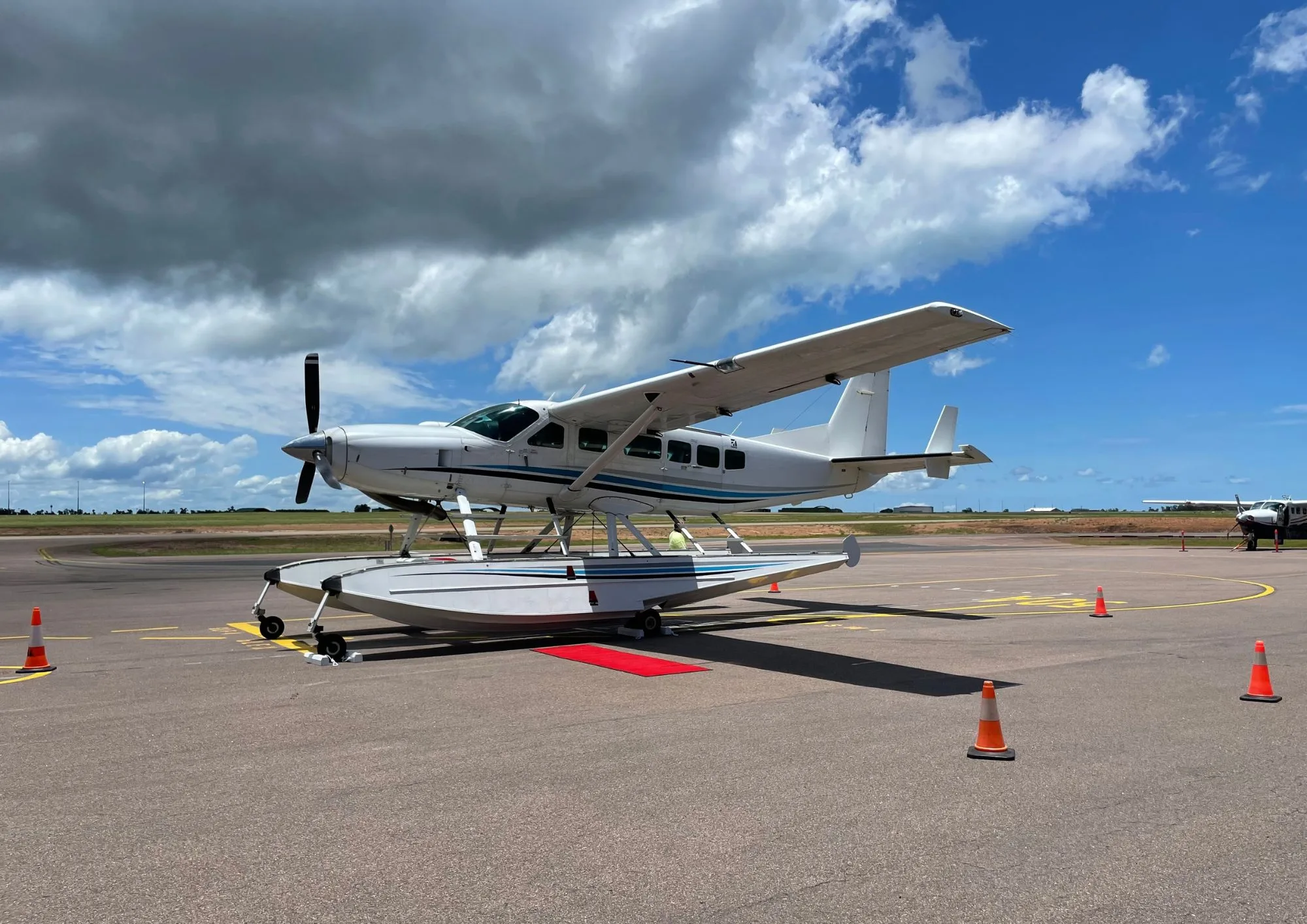 A seaplane parked on the tarmac with a red carpet leading to the door.