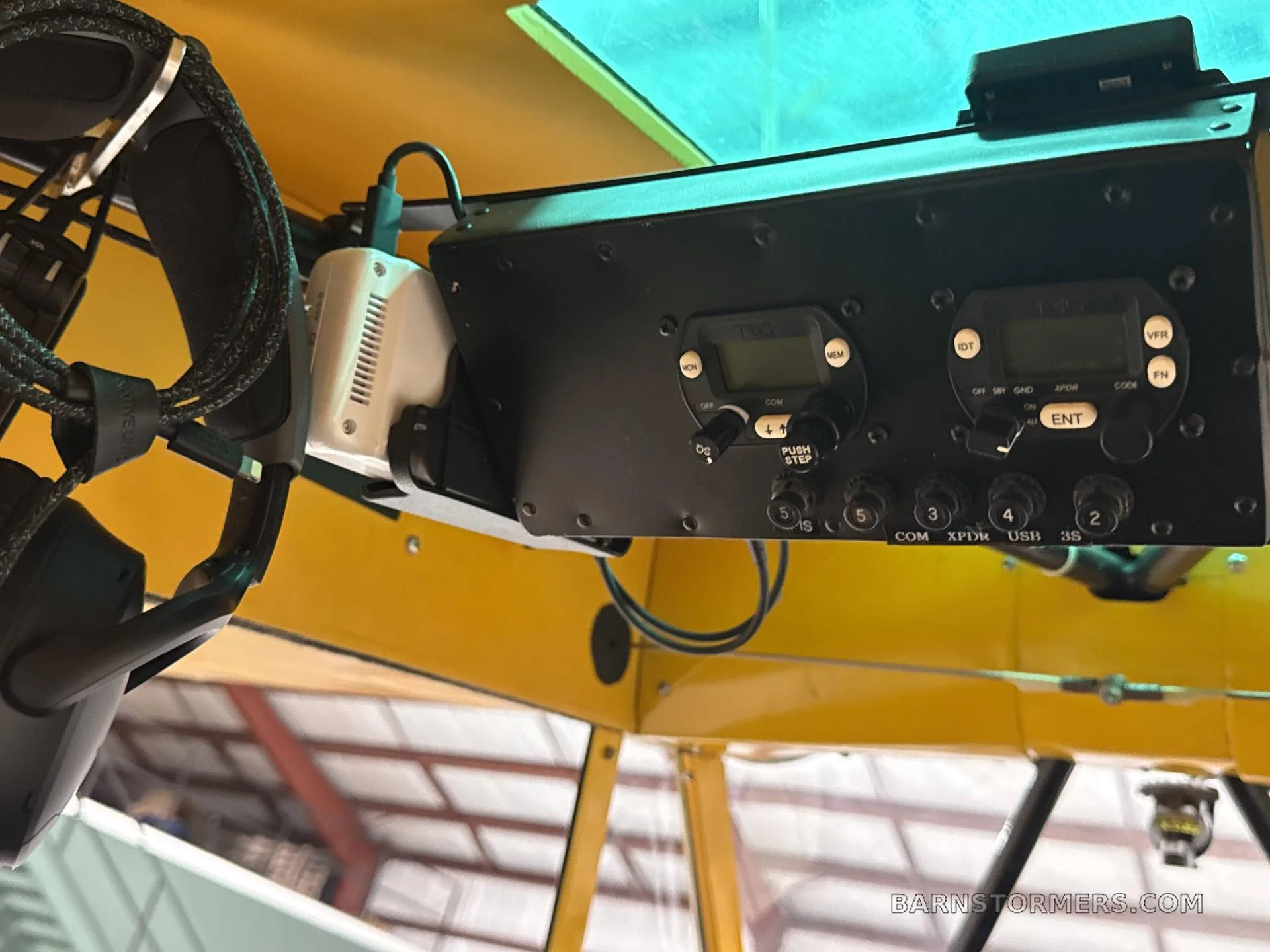 An overhead view of avionics and a headset mounted inside a yellow aircraft cabin.