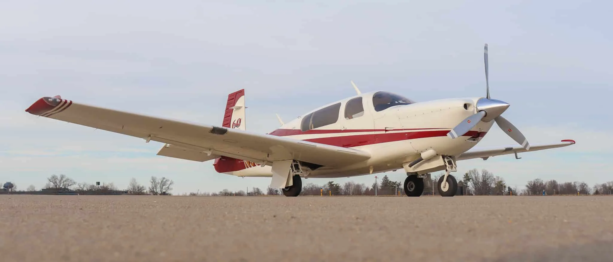 A white and red single-engine propeller aircraft, N993JT, parked on an airfield from a low angle.