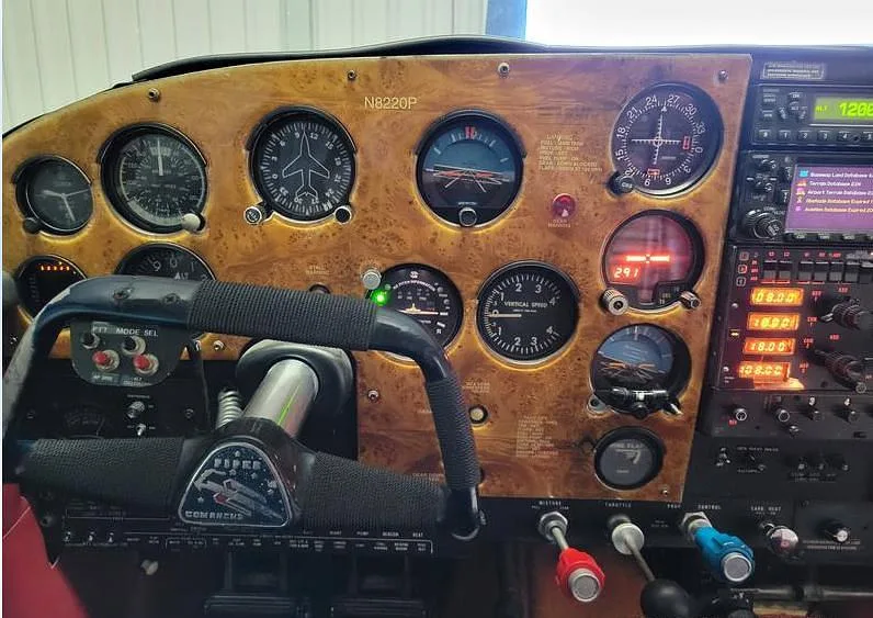 A full view of the aircraft's wood grain instrument panel, showing the yoke, gauges, and avionics with tail number N8220P.