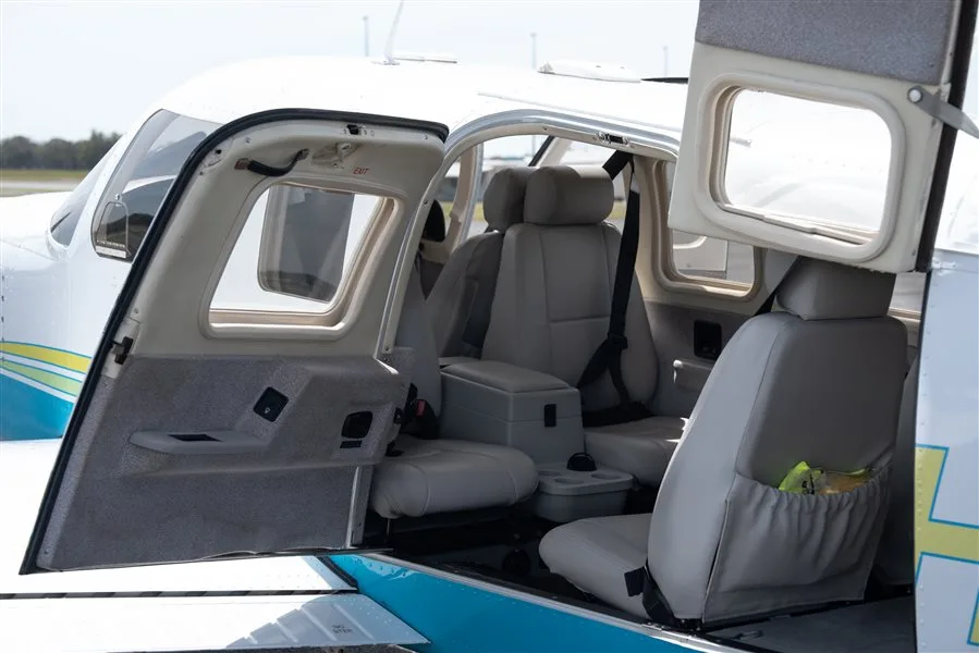 The light gray interior of an aircraft cabin with seats and an open door, showing the exterior paint scheme.