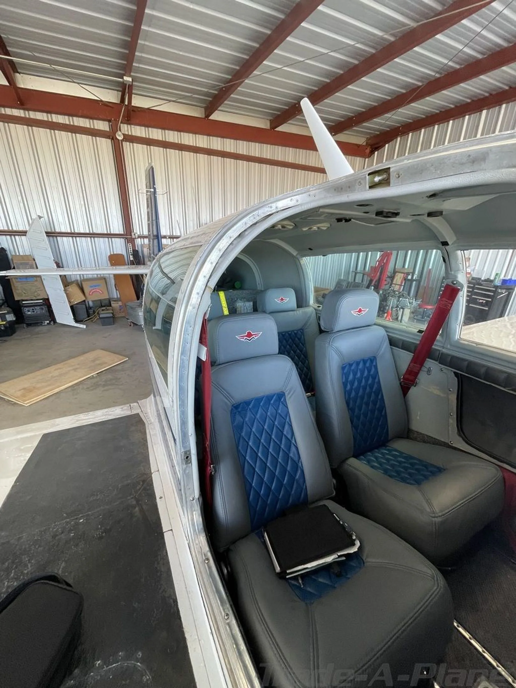 The aircraft's interior cabin with gray and blue quilted leather seats inside a hangar.