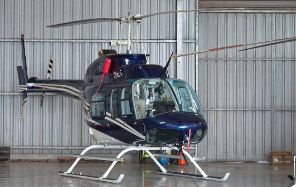 Front view of a blue and white Bell 206L-4 helicopter inside a hangar.
