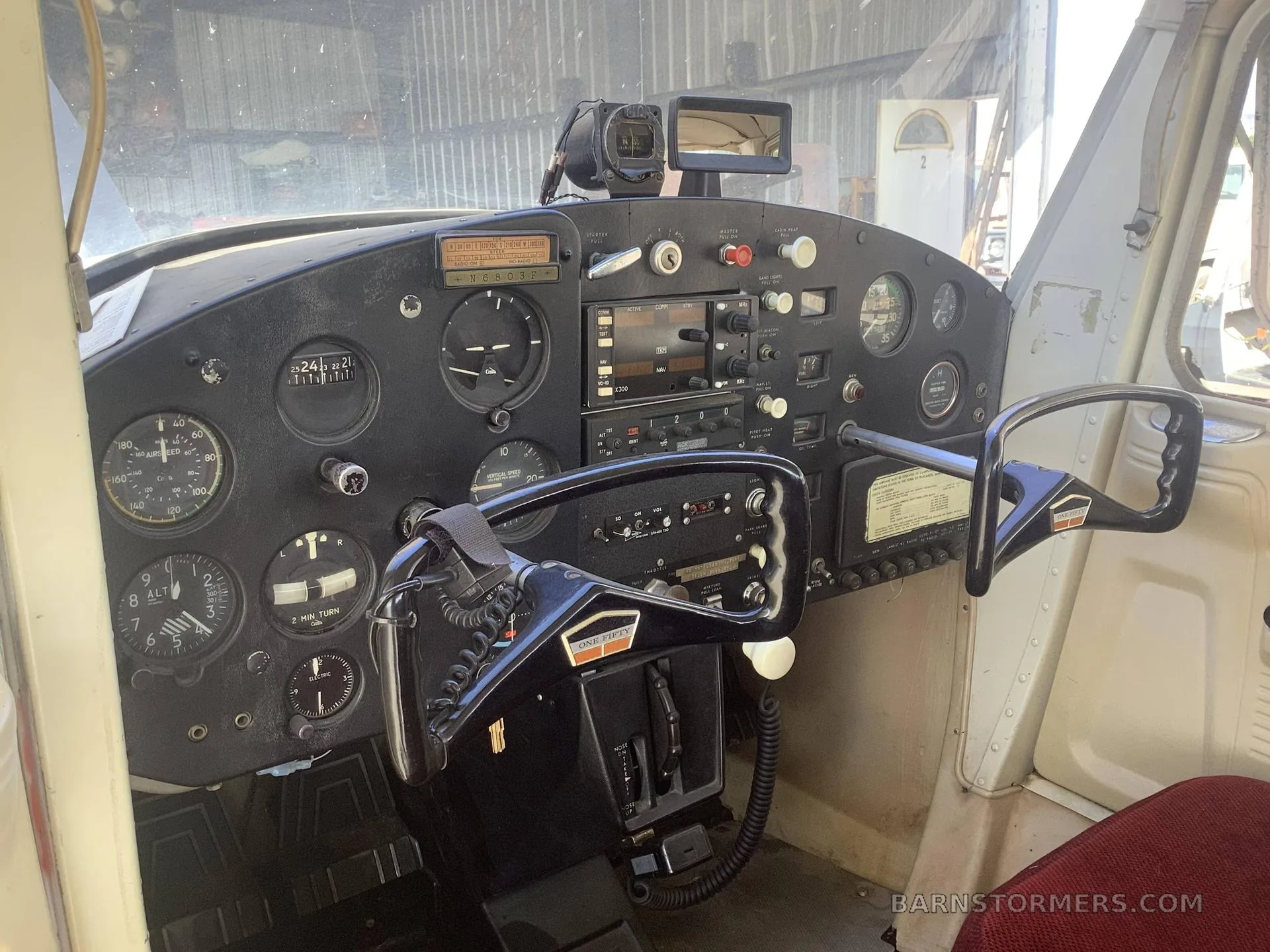 The cockpit of a small aircraft, showing the instrument panel with various gauges, radios, and two control yokes.
