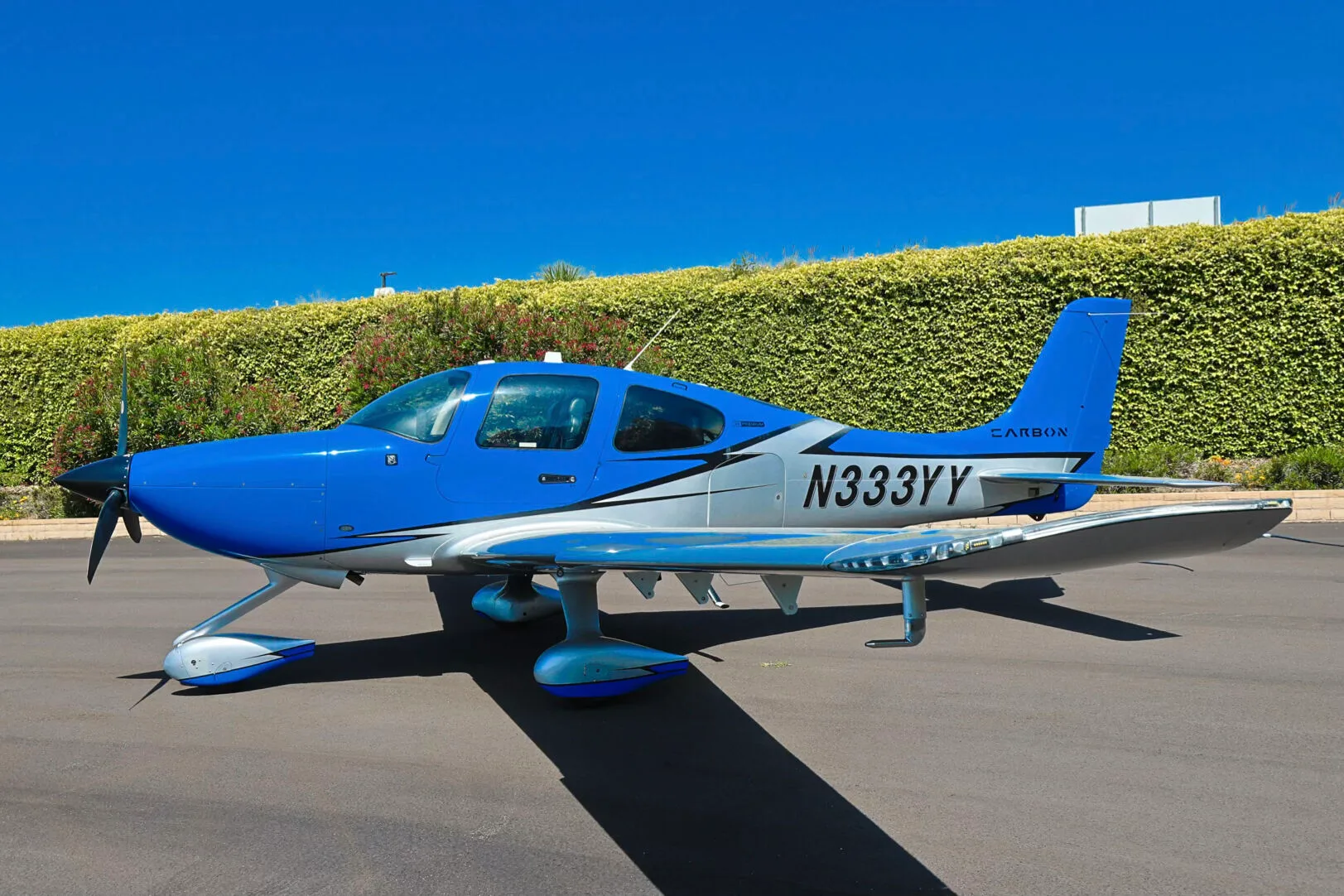 A side view of the blue and silver Cirrus SR20 aircraft N333YY with its wings extended, parked on an asphalt ramp.