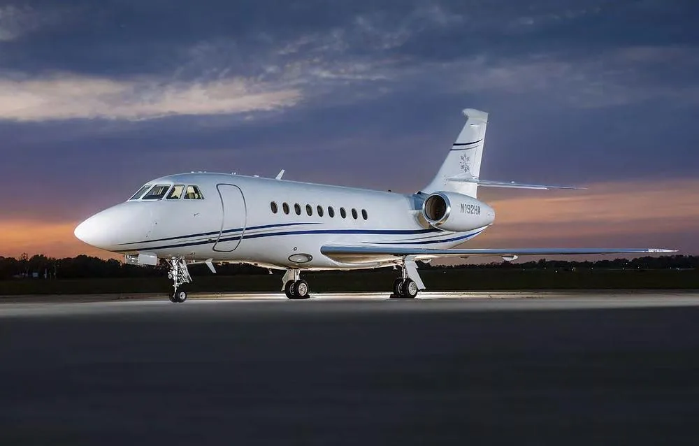 A Dassault Falcon 2000 business jet, registration N192HA, parked on an tarmac at sunset.
