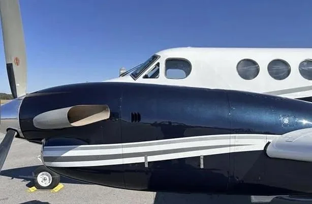 Close-up view of the front fuselage and propeller of a dark blue and white twin-turboprop aircraft.