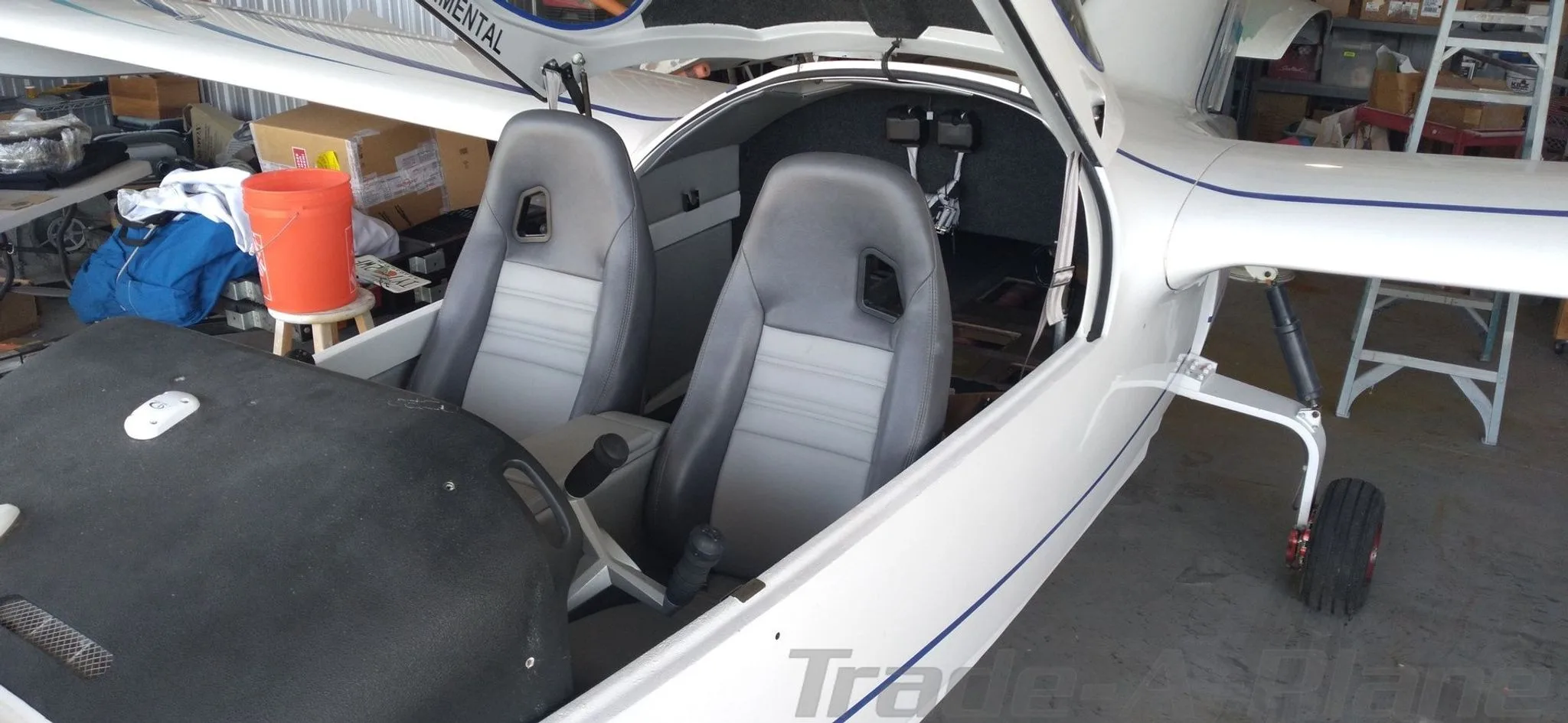A wider view of the Searey aircraft's interior, showing two grey and white seats and the open canopy.