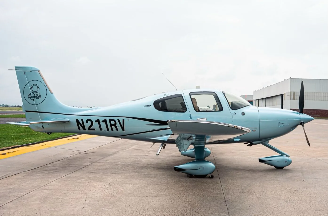 A light blue Cirrus SR22T aircraft with registration N211RV parked on an airfield.